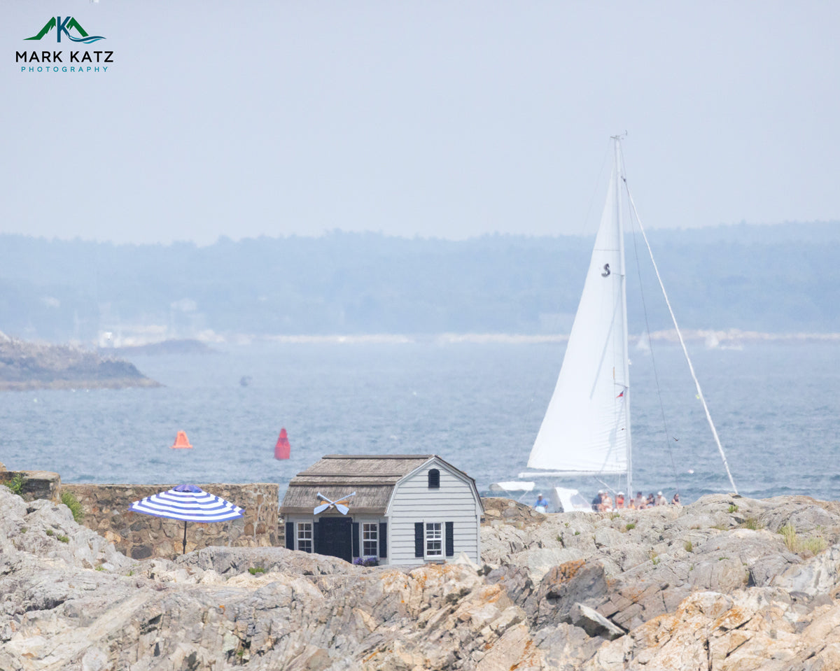 White sailboat sailing near rocky Marblehead coastline with harbor shack on a hazy summer day — nautical fine art wall print.