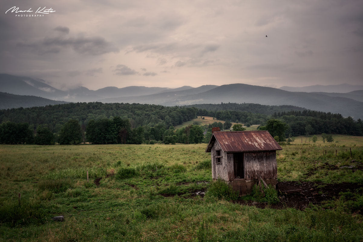Rural barn in lush green field under dramatic sky, rustic fine art photography for countryside decor.