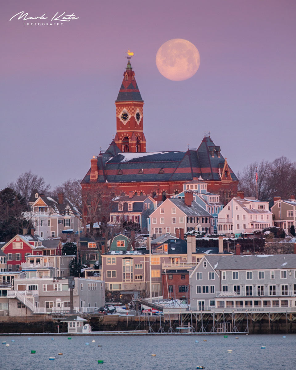Pink full moon rising above snowy rooftops and Abbot Hall in Marblehead