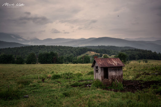 Rural barn in lush green field under dramatic sky, rustic fine art photography for countryside decor.