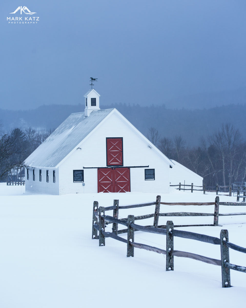 Patriotic Vermont barn painted red with snowy white roof under bright blue sky, fine art decor.