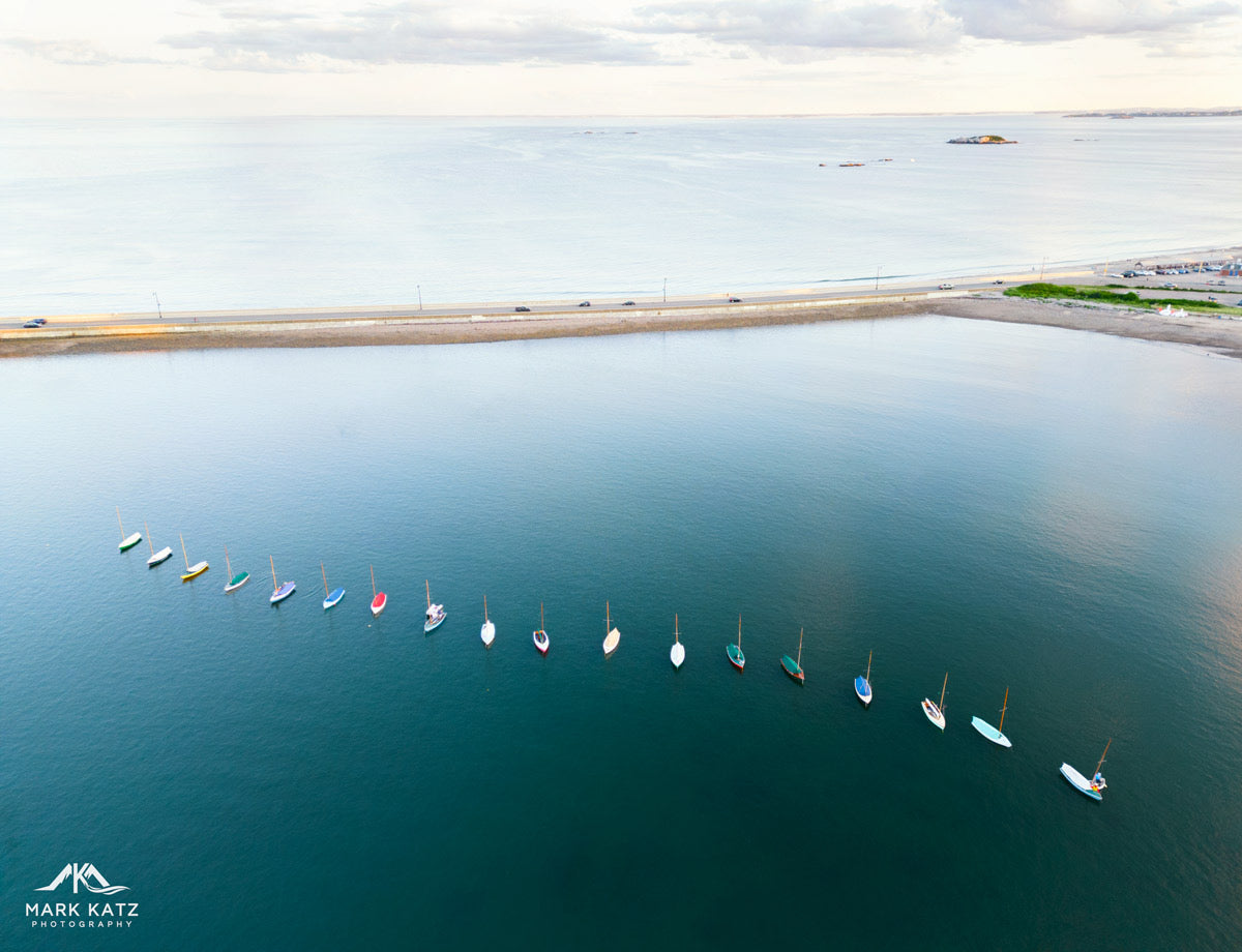 Colorful townie sailboats glowing like gemstones on harbor water, vibrant nautical fine art photography print.