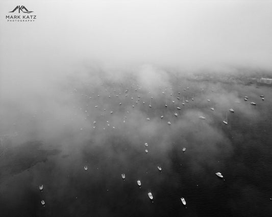 Lighthouse emerging through dense fog, mysterious coastal fine art photography for dramatic nautical decor.