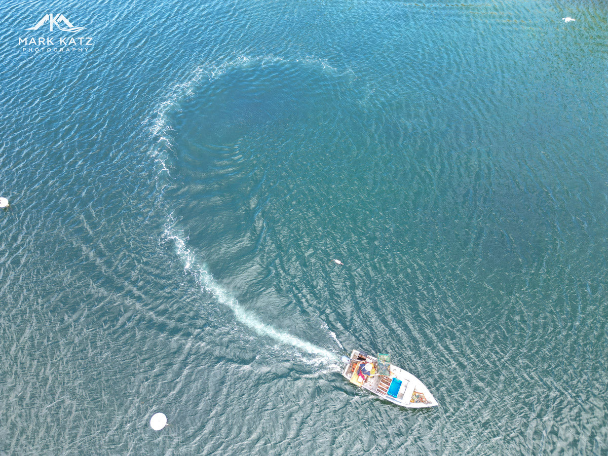 Boat turning across deep turquoise water, nautical fine art photography capturing maritime energy.