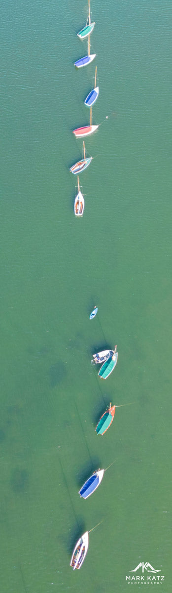 Boats aligned vertically in water, creating striking maritime pattern captured in aerial fine art photo.