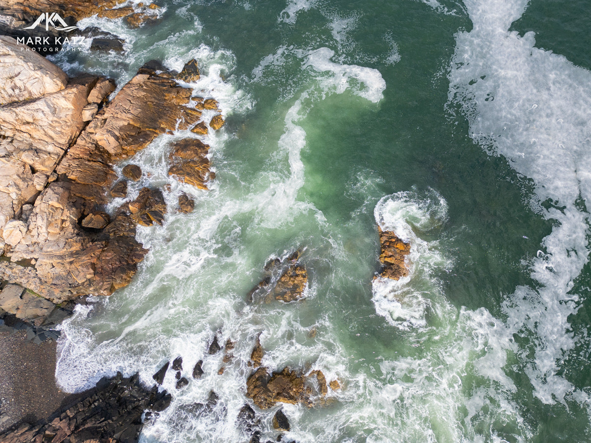 Raging ocean waves crashing against rocky cliffs with visible foam.