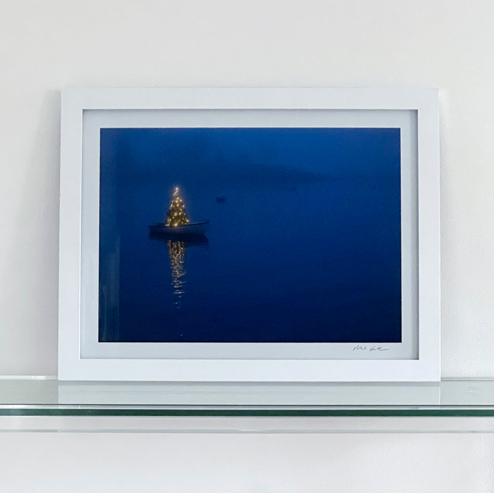 Framed photograph of a boat with a Christmas tree during blue hour