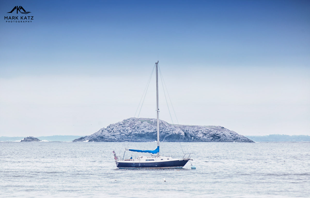 Minimalist sailboat floating on tranquil blue sea, serene nautical fine art photography piece.