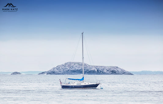 Minimalist sailboat floating on tranquil blue sea, serene nautical fine art photography piece.