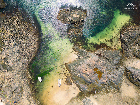 Boats hidden along rocky shoreline, coastal fine art photography highlighting secret maritime scenes.