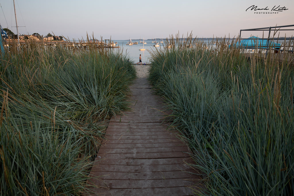 Person walking through tall grass under soft light, fine art photography evoking calm nature stride by.