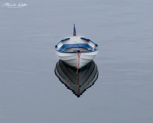 Single sailboat sitting solo and still in calm waters, minimalist nautical fine art photography.