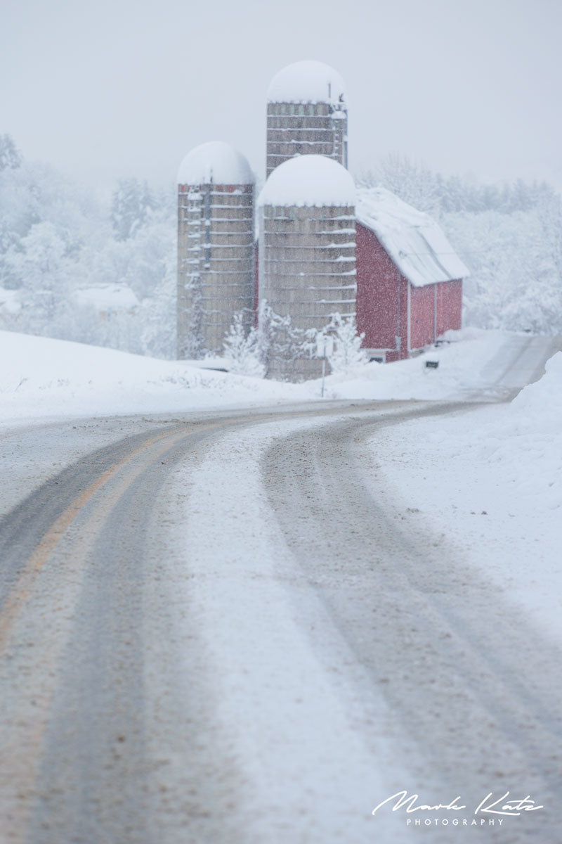 Snowy road stretching into distance, serene winter drive captured in peaceful fine art photography.