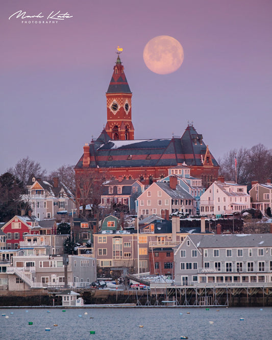 Pink full moon rising above snowy rooftops and Abbot Hall in Marblehead