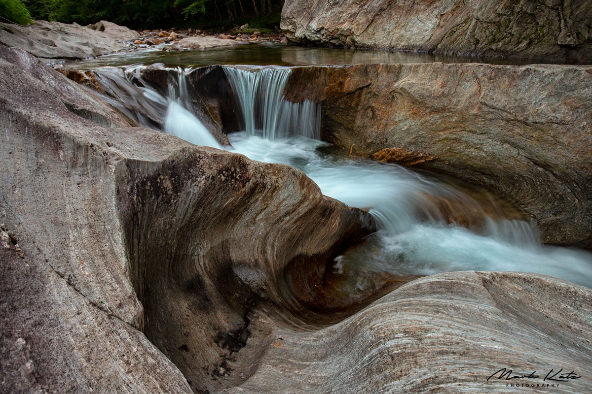 Water cascading over curvy rocks in dramatic flow, fine art photography for dynamic decor.