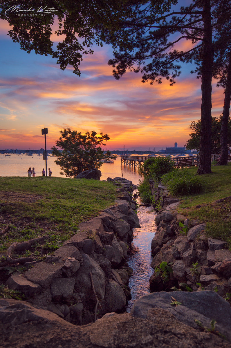 People gathered on coastal rocks watching brilliant sunset, communal end of day coastal fine art photo.