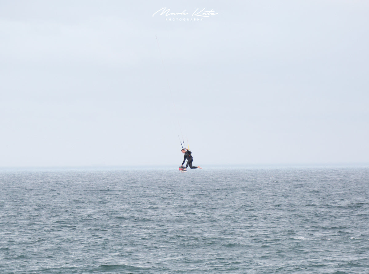 Kite boarder suspended in mid air over the ocean; minimalist nautical fine art photography for serene decor.