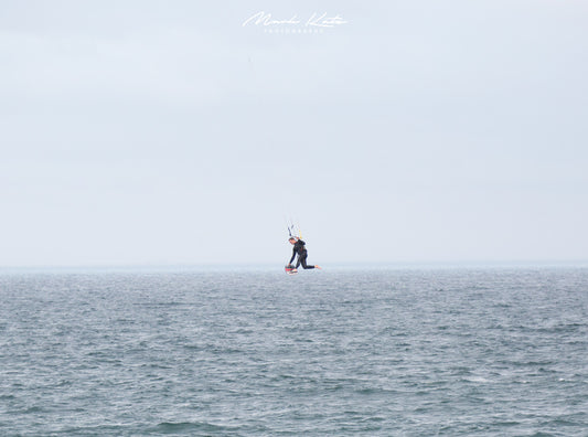 Kite boarder suspended in mid air over the ocean; minimalist nautical fine art photography for serene decor.