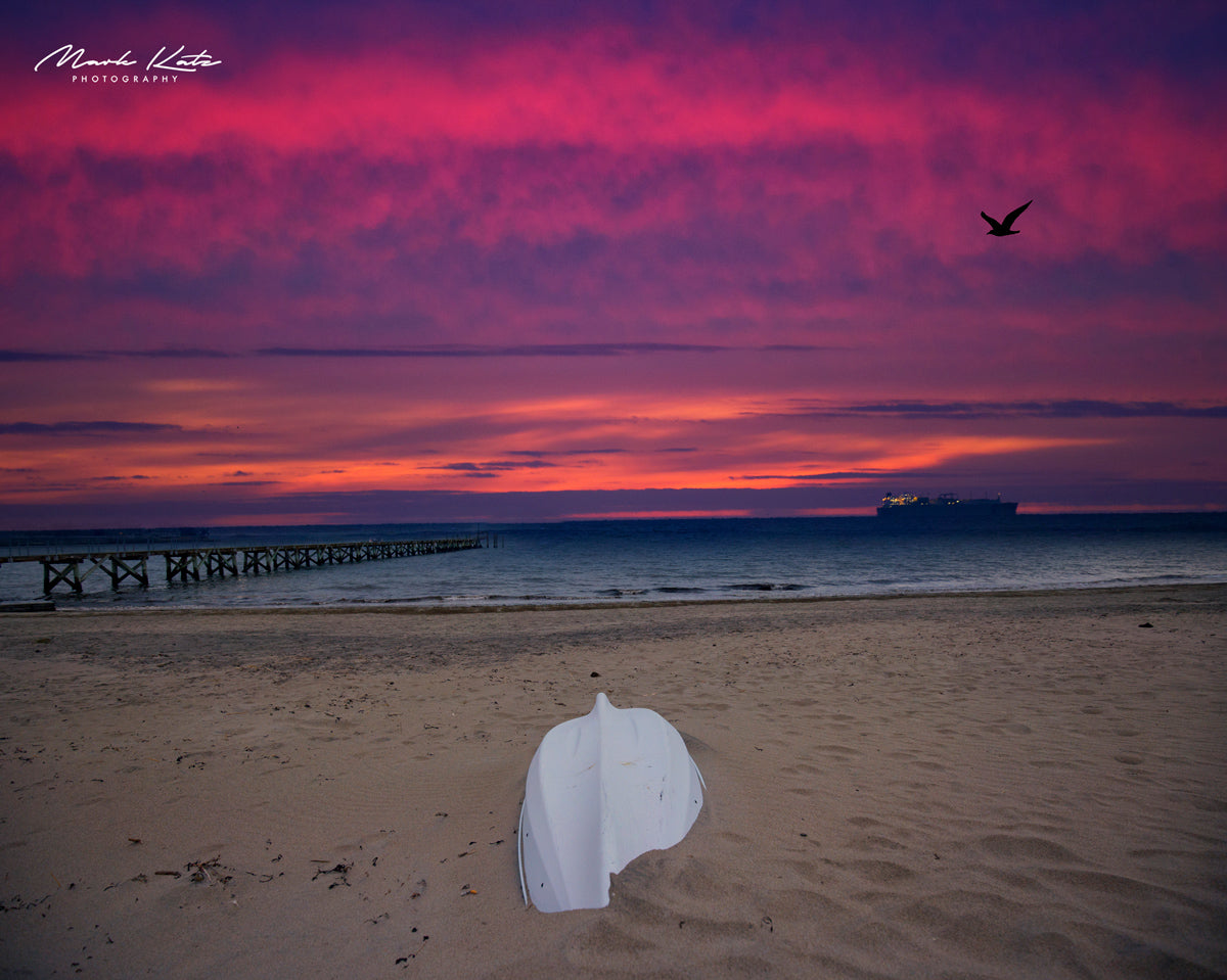 Lone boat marooned on sandy shore at low tide, coastal fine art photography capturing solitude.