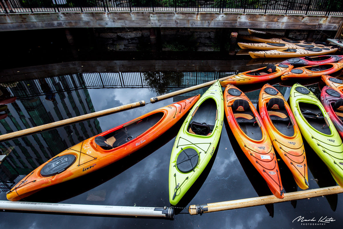Colorful kayaks lined up like dominos, playful nautical fine art photography perfect for vibrant interiors.