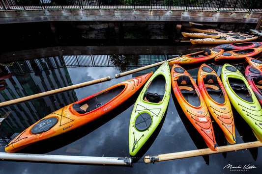 Colorful kayaks lined up like dominos, playful nautical fine art photography perfect for vibrant interiors.