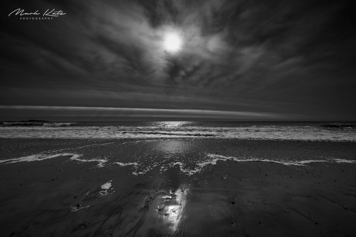 Black and white photo capturing distilled light and shadows over ocean waves, modern minimalist photography.