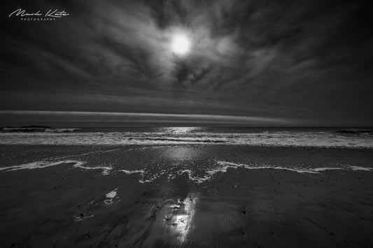 Black and white photo capturing distilled light and shadows over ocean waves, modern minimalist photography.